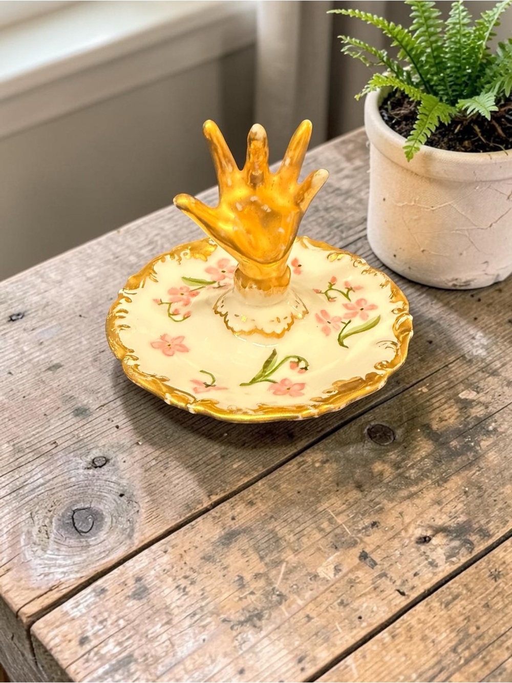 A T & V Limoges porcelain ring holder with a gold hand and floral decoration.